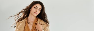Genç bir kadın şık bir sonbahar kıyafetiyle zarif bir şekilde ışıldıyor, rahat bir stüdyoda mevsimlik moda trendleri sergiliyor..