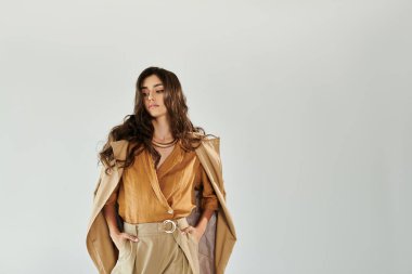 Genç ve güzel bir kadın modaya uygun bir sonbahar kıyafetine güveniyor. Modern bir stüdyo için mükemmel bir stil..