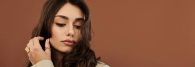 Güzel bir kadın şık bir sonbahar elbisesi içinde şık poz veriyor, sıcak bir stüdyo ortamında mevsimlik modayı vurguluyor..