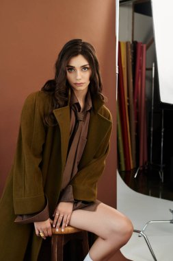 Genç bir kadın, sonbaharın özünü moda bir kıyafetle yakalıyor. Stüdyo ortamında tarz ve zarafet yayıyor..