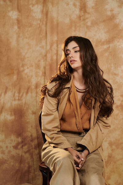 A beautiful woman elegantly poses in a chic autumn outfit, highlighting seasonal style and warmth in a cozy studio environment.