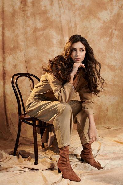 A young woman elegantly poses in a chic autumn outfit, highlighting seasonal trends in a warm studio atmosphere.