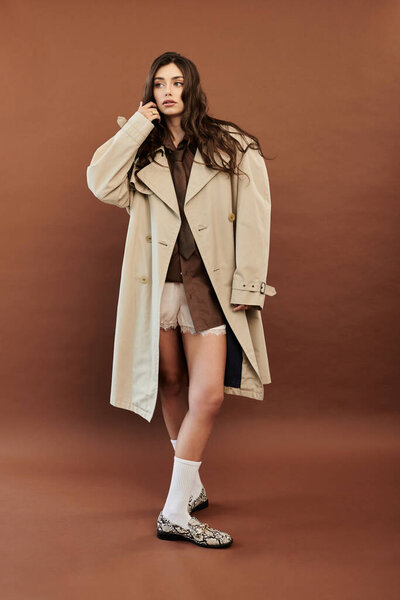 Молодая и красивая модель уверенно позирует в модном осеннем ансамбле, излучая тепло и стиль.