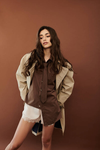 Изящная женщина моделирует шикарный осенний ансамбль в уютной студии, источая уверенную и стильную атмосферу, идеальную для сезона.