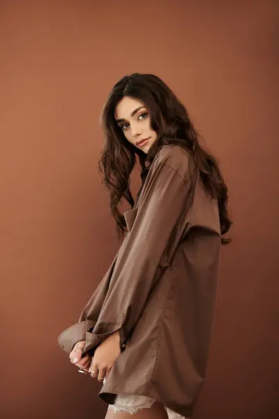 stock image A beautiful young woman poses effortlessly in a chic autumn outfit, embodying warmth and elegance in a cozy studio atmosphere.