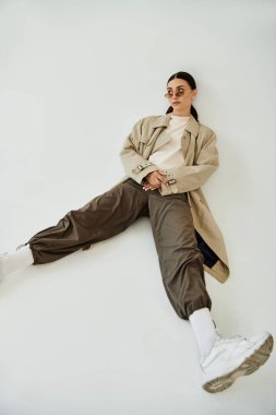 Genç, güzel bir kadın zarif bir sonbahar elbisesi içinde modern bir stüdyo alanına güvenerek poz veriyor..