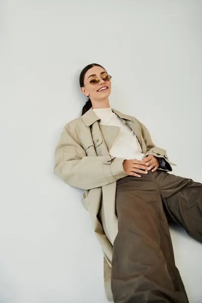 stock image A young woman exudes confidence in a chic autumn outfit, posing gracefully in a stylish studio space.