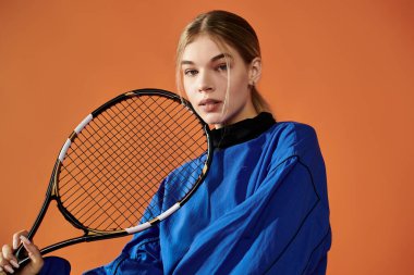 Yetenekli bir sporcu, elinde tenis raketi tutarken duygularını ifade eder. Kararlılığını somutlaştırır..