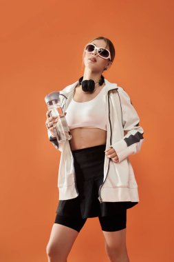Ateşli bir sporcu kadın su şişesini tutarken gücünü ve stilini sergiliyor..