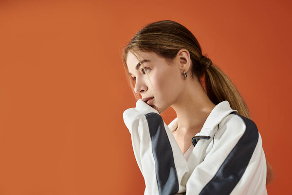 A stunning athlete shows deep emotion while posing thoughtfully against a colorful backdrop.