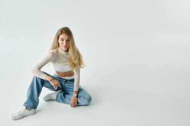 Şık, genç bir kadın yerde rahat bir şekilde oturuyor, stilini ve güvenini sergiliyor..