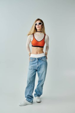 Kendine güvenen genç bir kadın spor modasına uygun yaz kıyafetleri ve güneş gözlükleri minimalist bir alanda..