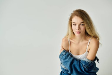 Kadın düşünceli bir şekilde kameraya bakıyor, doğal güzelliğini ve rahat stilini gösteriyor..