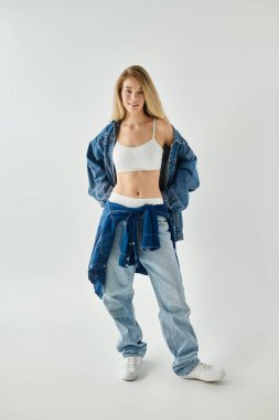 Kendine güvenen genç bir kadın, temiz ve parlak bir zemine karşı günlük kot giyip poz verir..