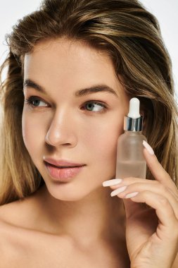 Işıl ışıl cildi olan genç bir kadın rahatlatıcı bir serum sergiliyor..