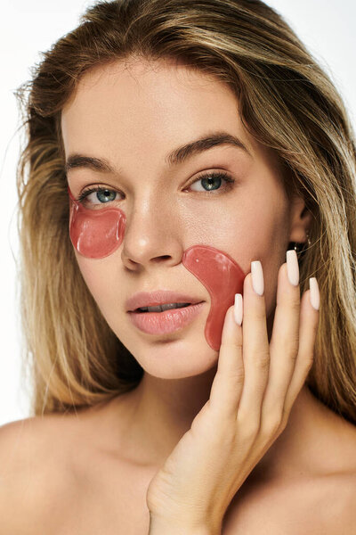 Молодая женщина наслаждается ритуалом по уходу за кожей, нанося освежающие гелевые пластыри, мягко светясь.