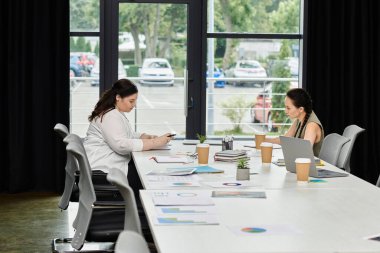 İki profesyonel, şık bir ofis ortamında işlerini tartışıyor..