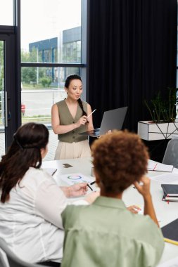 Dengeli bir iş kadını, meslektaşlarını modern bir ofis ortamında sunumla meşgul ediyor..
