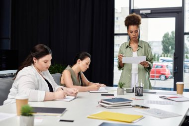 Three professional women engage in a focused discussion surrounded by office materials. clipart