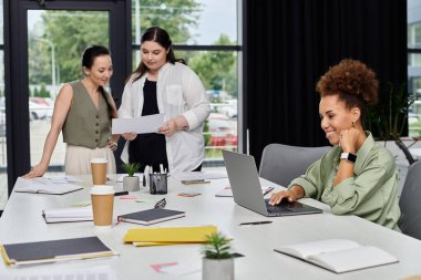 Üç profesyonel kadın şık bir ofis çalışma alanında dinamik tartışmalara giriyorlar..