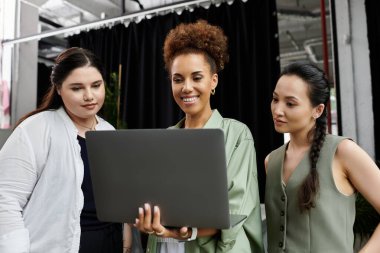 Zarif kadınlar, çağdaş ofis ortamında fikirlerini ve sezgilerini paylaşan bir dizüstü bilgisayarla uğraşırlar..