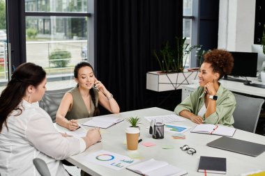 Bir grup profesyonel kadın modern bir ofis alanında yaratıcı bir işbirliği içinde..