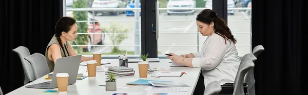 stock image Two professional women work intently at a chic office table, basking in natural light.