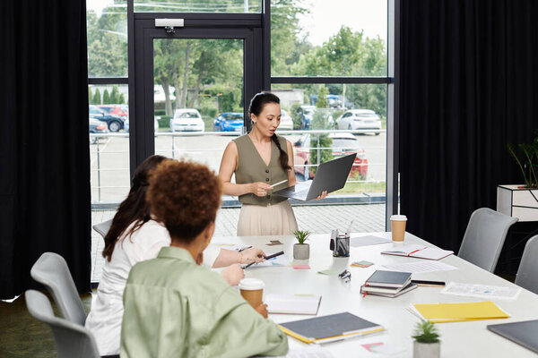 A group of professional women engage in dynamic discussions while working in a modern office space.