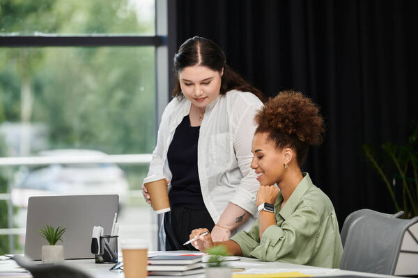 Две элегантные женщины участвуют в продуктивном обсуждении во время просмотра документов в офисе.