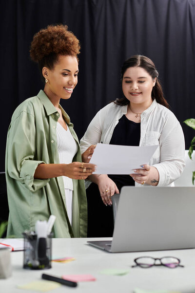 Two professional women discuss documents together in a stylish office environment.