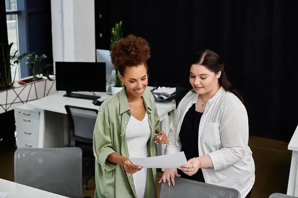 stock image Two professional women discuss project details, exchanging ideas in a contemporary workspace.