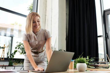Neşeli genç bir profesyonel, canlı bir ofis atmosferinde dizüstü bilgisayarıyla meşgul oluyor..