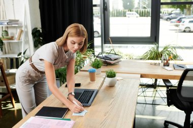 Motive olmuş genç bir iş arkadaşı şık bir ofis ortamında çalışırken not alır..