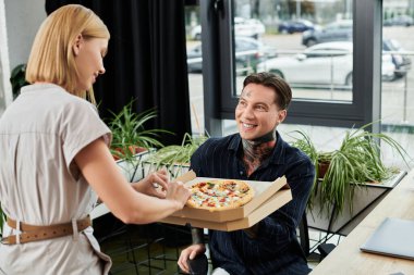 İki genç iş arkadaşı öğle arasında pizzanın tadını çıkarırken keyifli bir anı paylaşıyorlar..