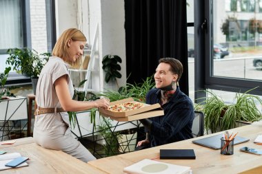 İki genç profesyonel, canlı ofis ortamlarında keyifli bir pizza molası veriyor..