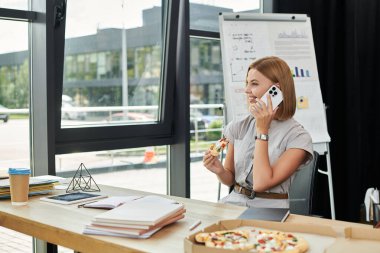Neşeli bir iş arkadaşı, canlı bir ofis molası sırasında pizza ve telefon dinlemekten zevk alır..