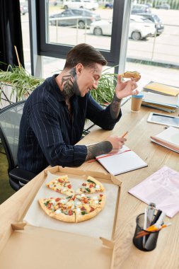 Genç adam ofiste pizza yemekten hoşlanıyor..