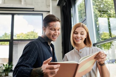 İki genç profesyonel birlikte bir projeyi incelerken hevesle iş birliği yapıyorlar..