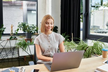 Genç bir profesyonel, canlı yeşil ofis ortamında dizüstü bilgisayarla çalışmaktan zevk alır..