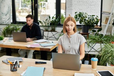 Bir çift genç profesyonel, bitkilerle dolu canlı bir ofiste iş birliği yapıyor..