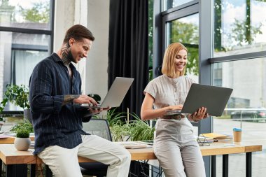 Two young coworkers collaborate at a chic office desk, boosting teamwork and creativity. clipart