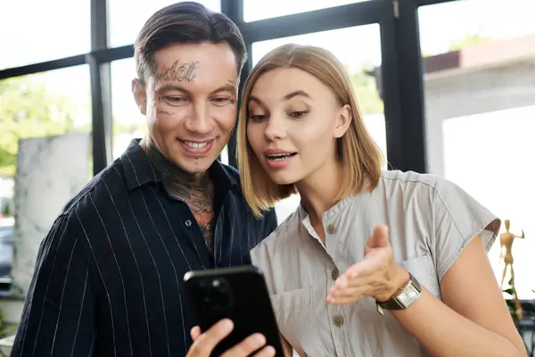 stock image A pair of young colleagues eagerly share a moment over their smartphone, smiling and laughing.