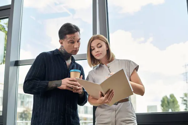 stock image Two colleagues discuss ideas while reviewing documents in a modern office setting.