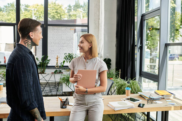 Two coworkers share a light hearted discussion in a bright and stylish workspace.