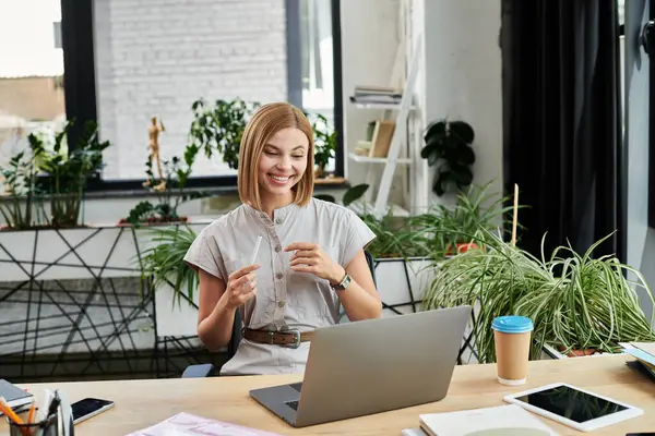 stock image A young professional enthusiastically participates in a virtual meeting surrounded by greenery.