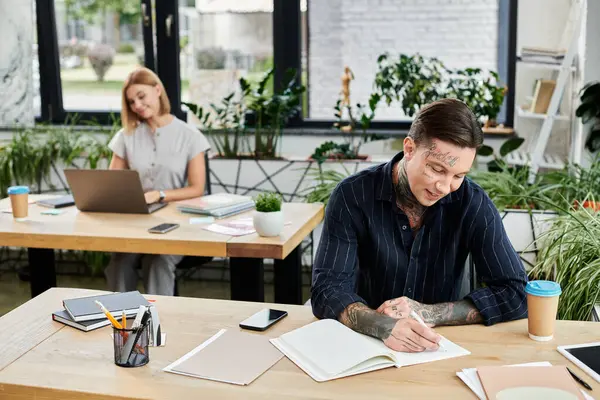 stock image Two young coworkers engage in productive tasks while surrounded by vibrant office plants.