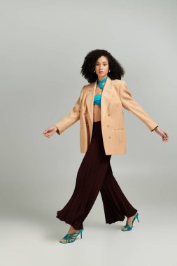 Kendine güvenen bir kadın canlı kıyafetini sergiliyor. Moda ve duruş tarzını modern bir ortamda sergiliyor..