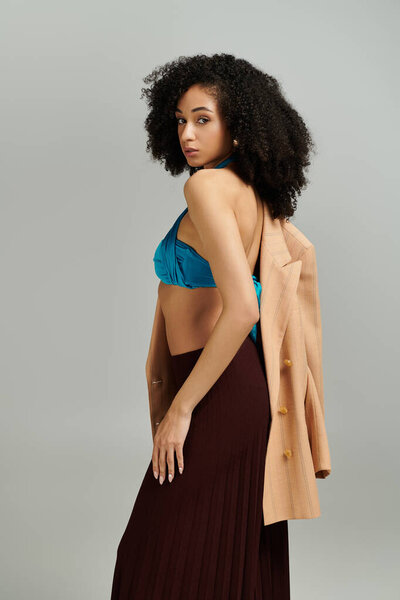 Модная женщина уверенно стоит, смешивая случайные и шикарные элементы в своей одежде.