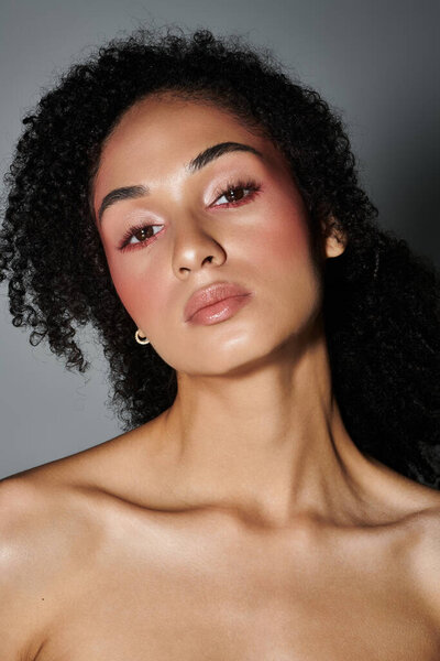 Модная женщина подчеркивает свой уникальный стиль и артистизм с смелым макияжем и уверенной позе.