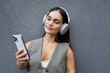 Neşeli bir gülümsemesi olan genç bir esmer kadın açık havada müzik dinler, kendini tamamen boş ve rahatlamış hisseder..